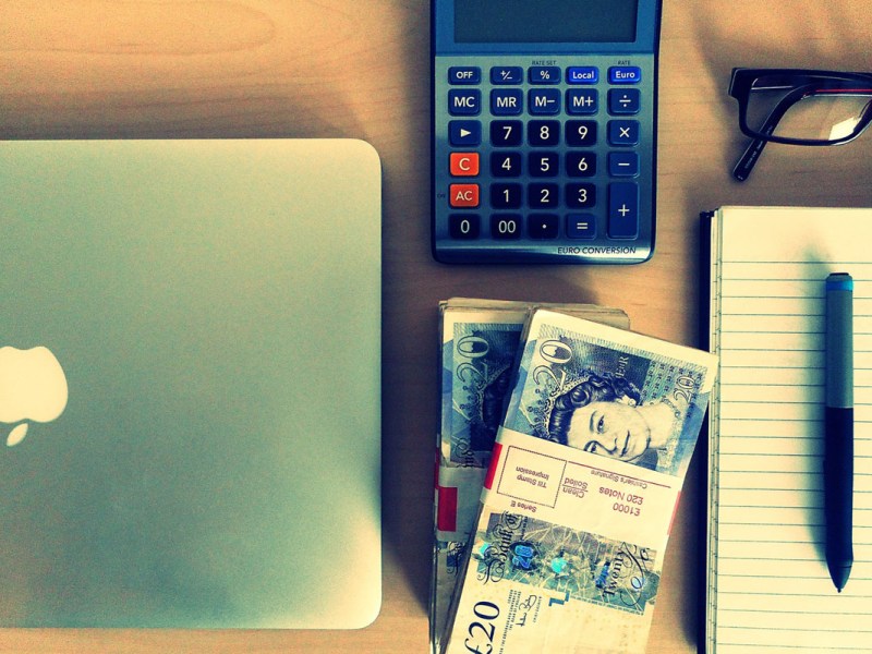 Geld und Taschenrechner neben Notebook