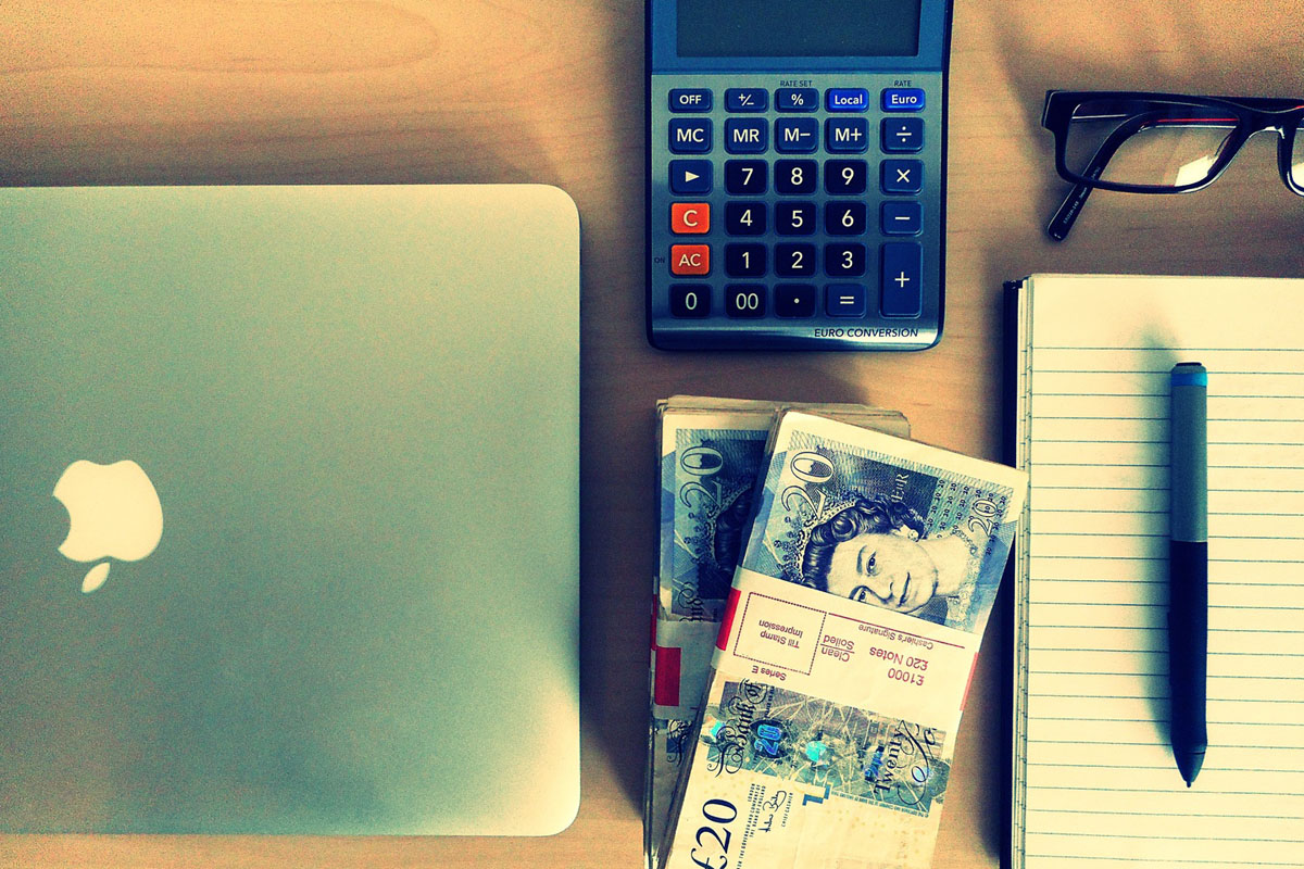 Geld und Taschenrechner neben Notebook