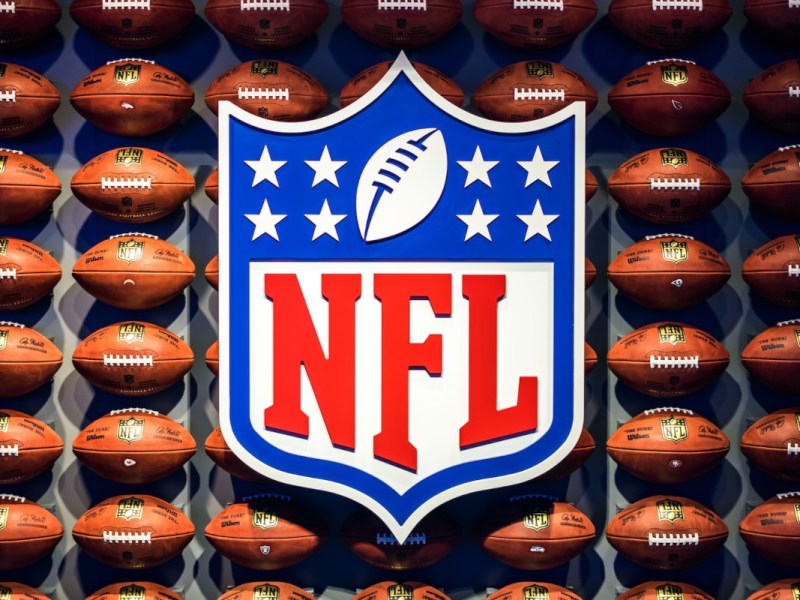 NFL Logo vor Regal mit vielen Footballs
