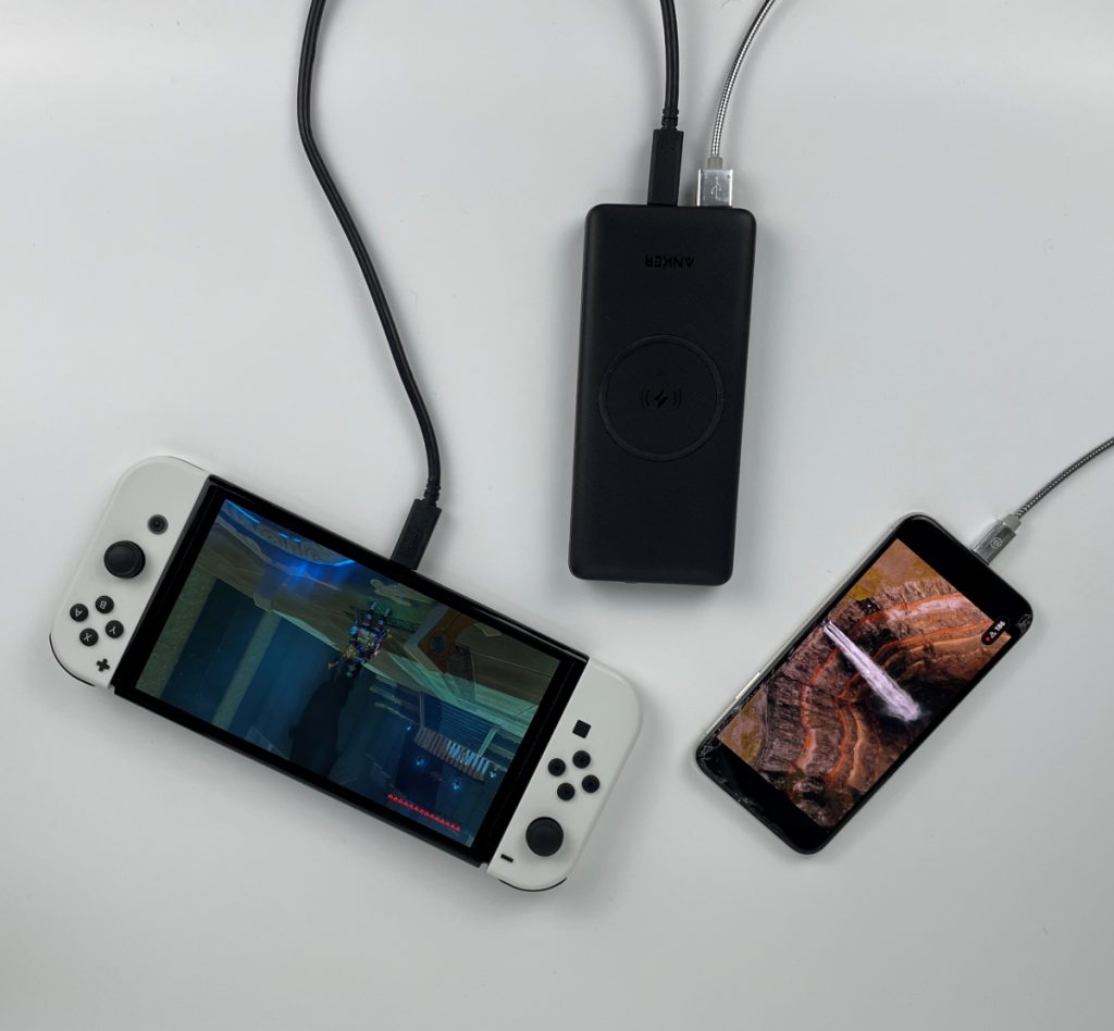 Weiße Switch neben schwarzer Powerbank neben Smartphone von oben; mit Kabeln verbunden