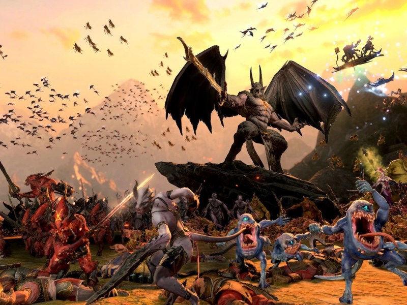 Artwork von Total War: Warhammer 3 zeigt viele unterschiedliche Kreaturen mit Waffen, die sich nach links bewegen vor Bergkulisse
