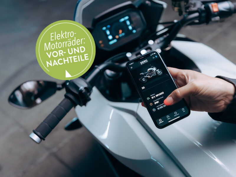 Eine Frau steht an ihrem Elekromotorrad und hat auf dem Handybildschirm die dazugehörige App geöffnet.
