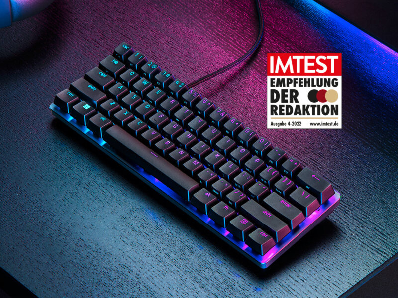 Black Razer Huntsman keyboard partially lit from above on dark table with IMTEST stamp 