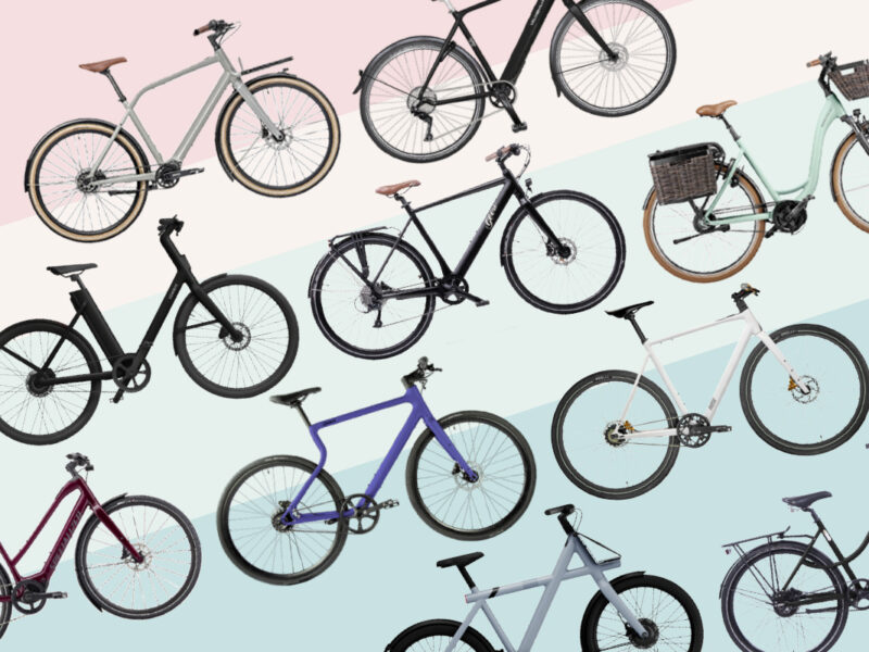 Verschiedene Urban-E-Bikes schräg in Reihe angeordnet vor Hintergrund mit Pastellstreifen
