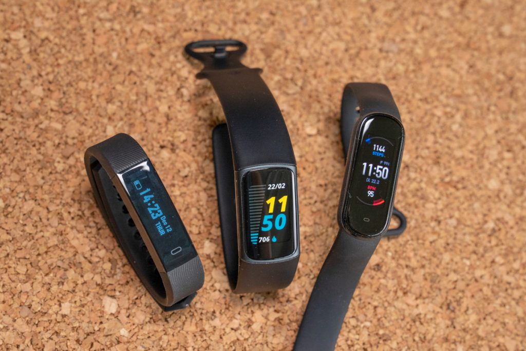 Three black fitness trackers next to each other on cork bottom