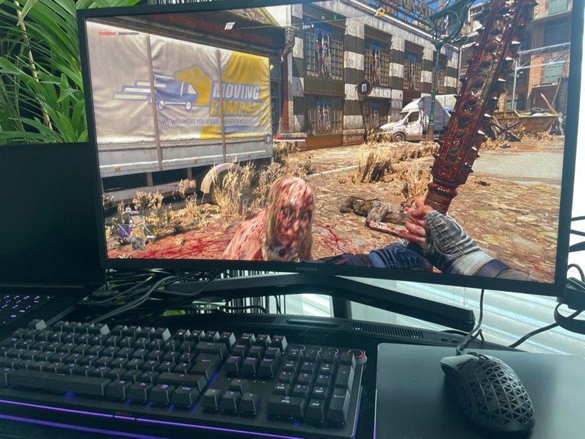 Computerbildschirm zeigt Shooter-Spiel, davor Tastatur und Asus-Maus im Test