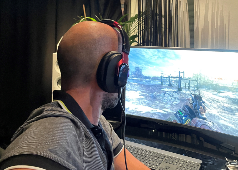 Mann von hinten mit Headset vor Gaming Monitor