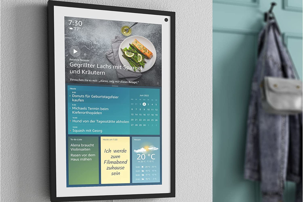 Echo Show 15 hÃ¤ngt mit schwarzem Rahmen hochkant an grauer Wand neben tÃ¼rkiser Garderobe und zeigt ein Rezept und Notizen an