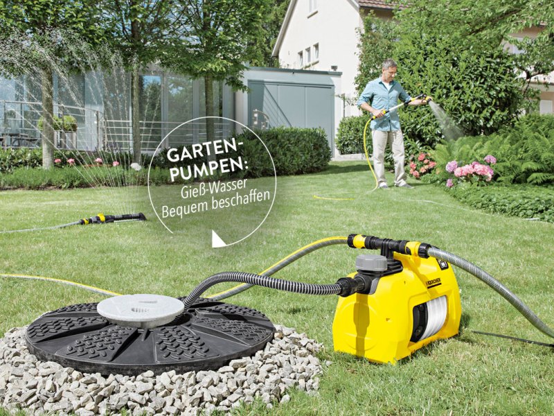 Mann gießt mit einem Schlauch Pflanzen im Garten. Das Wasser dafür wird von einer Gartenpumpe aus einem Brunnen gepumpt.