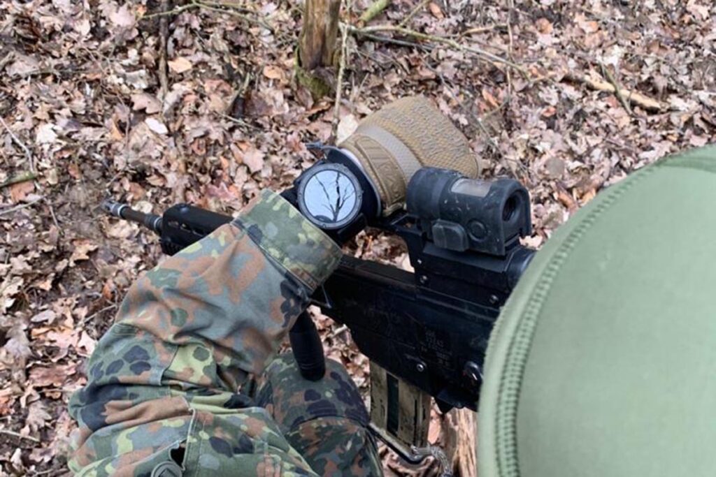 Ein Soldat mit einem Gewehr sieht auf seine Uhr
