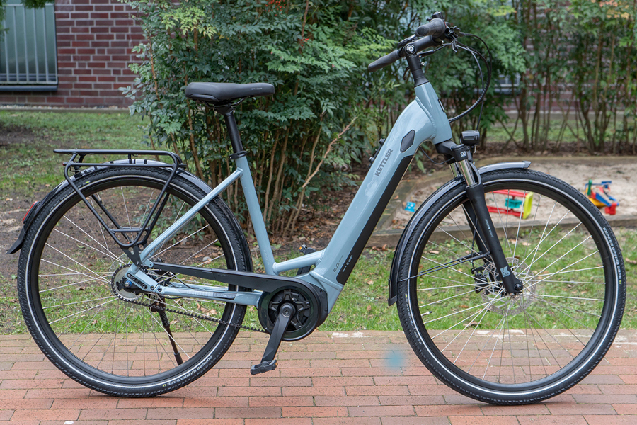 Grünes Trekking-E-Bike von Kettler vor Garten