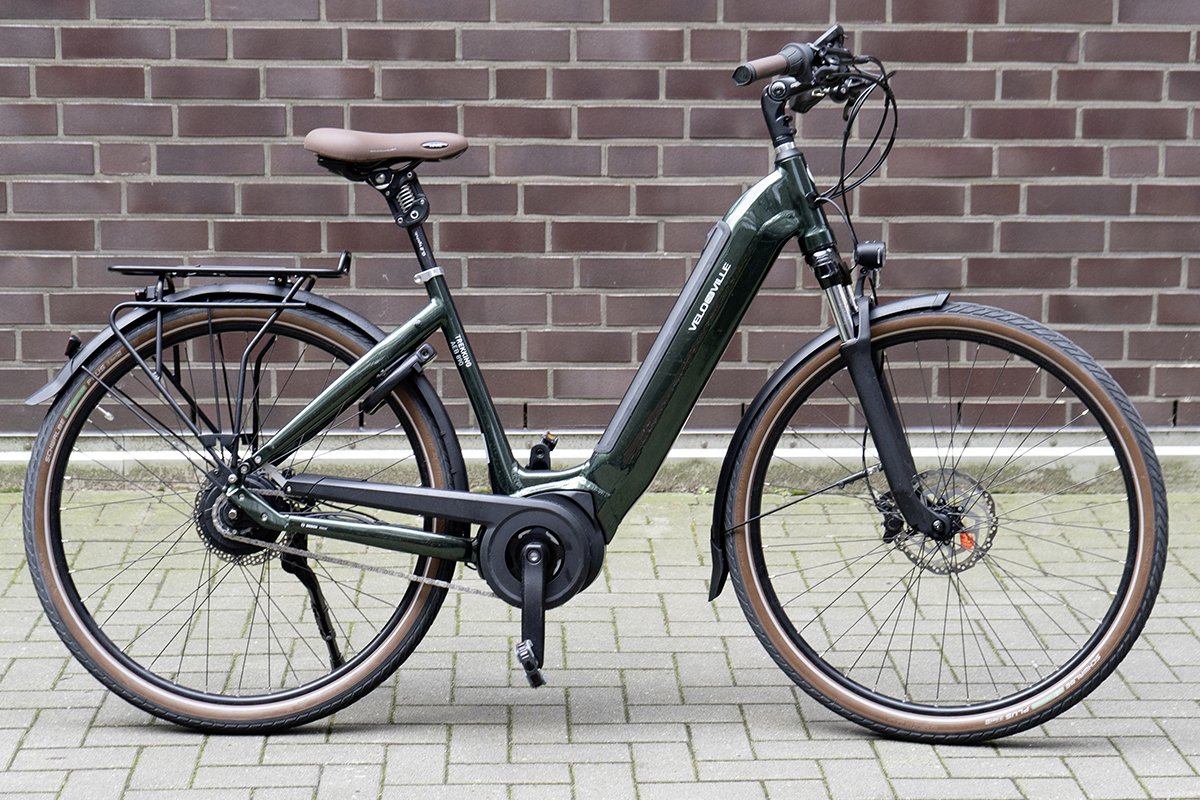 Dunkles Trekking-E-Bike von Velo de Ville vor Steinwand