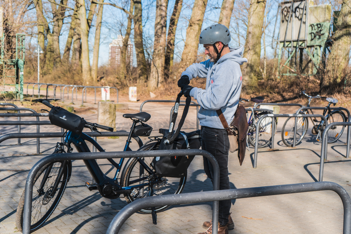 Mann schließt Trekking-E-Bike an Fahrradständer an