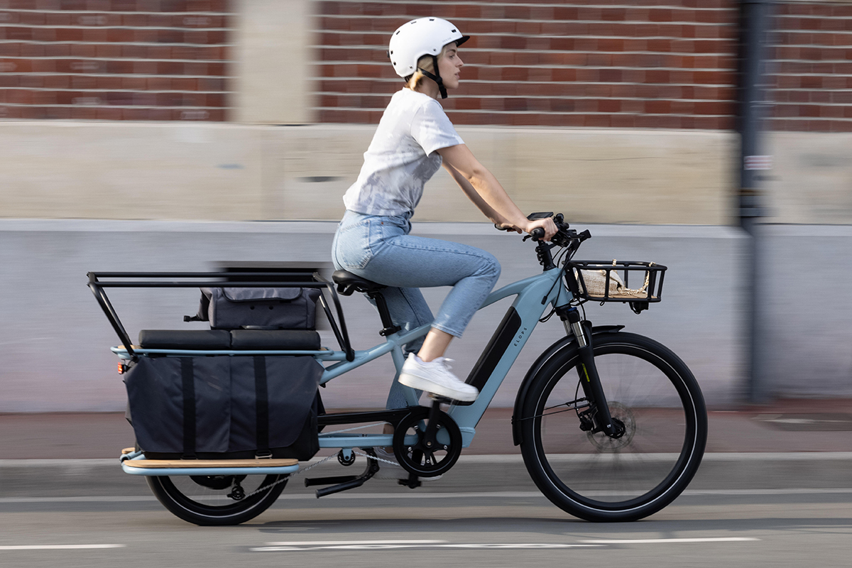 Das E-Lastenfahrrad R500E Langtail von Decatholn in Fahrt: Eine junge Frau ist damit in der Stadt unterwegs.