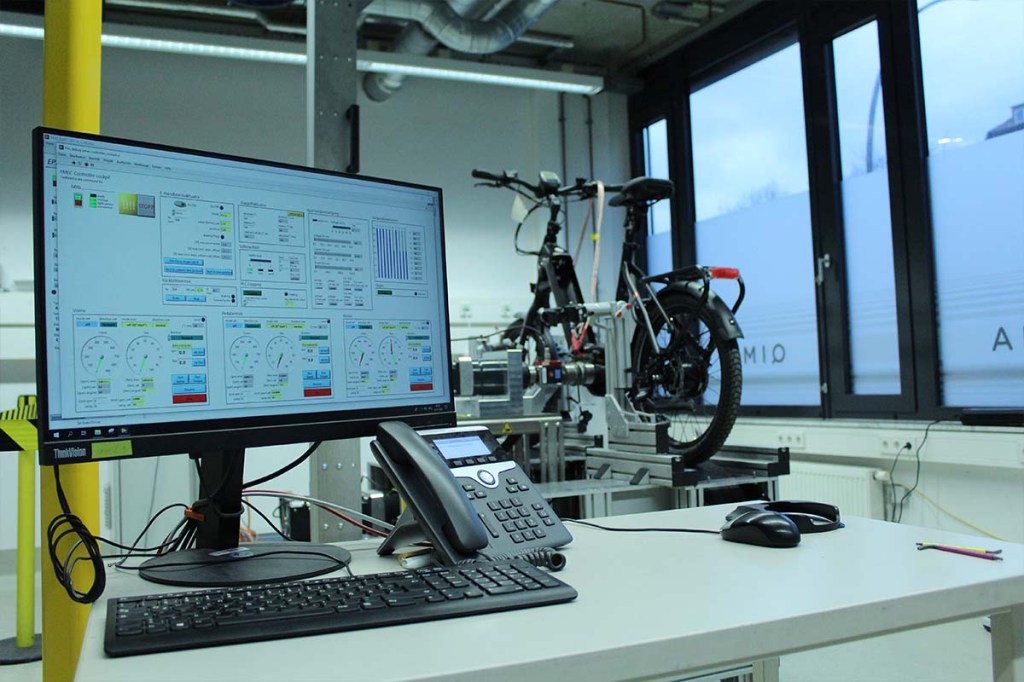 E-bike auf einem Prüfstand, im Vordergrund sieht man einen Monitor mit Messdaten