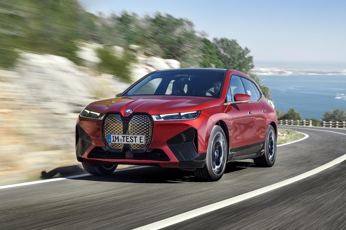 Der BMW iX in Rot auf fahrend einer Straße.