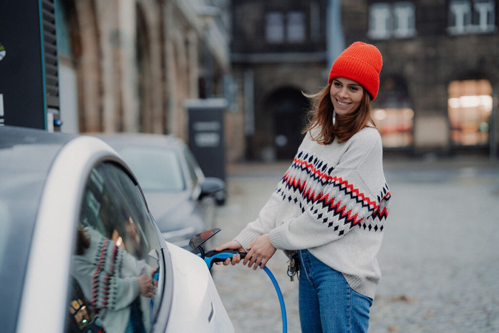 Eine Frau lädt ein Elektroauto mit neuem Strom auf.