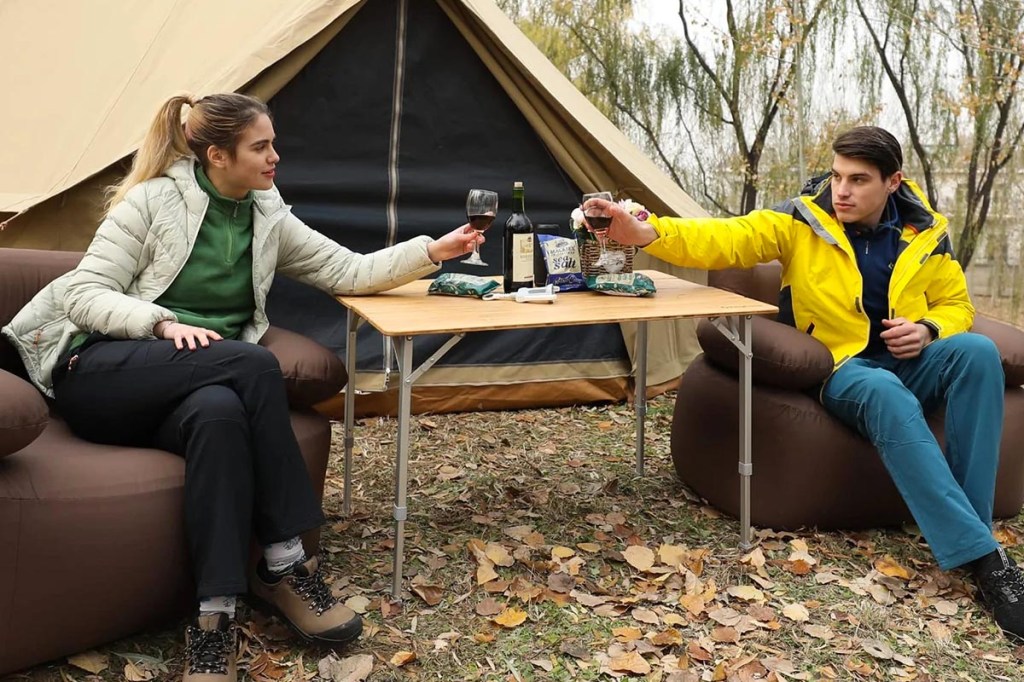 Mann und Frau an Tisch draußen im Herbst vor Zelt