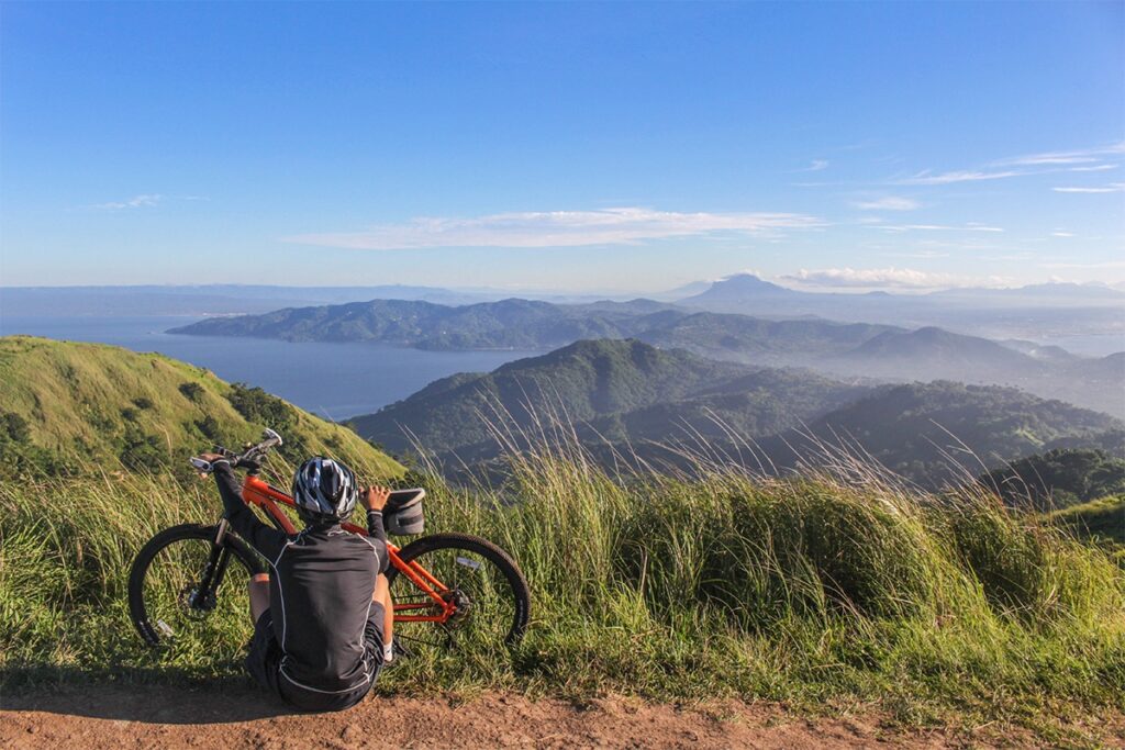 Fahrradfahrer mit Rad vor Bergkulisse