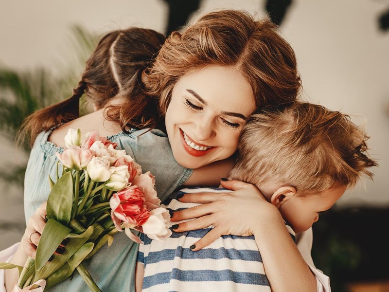 Eine mutter umarmt ihre beiden Kinder