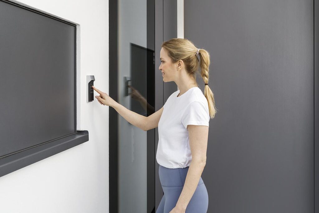 Eine Frau betätigt das Homematic IP Keypad an der Hauswand.
