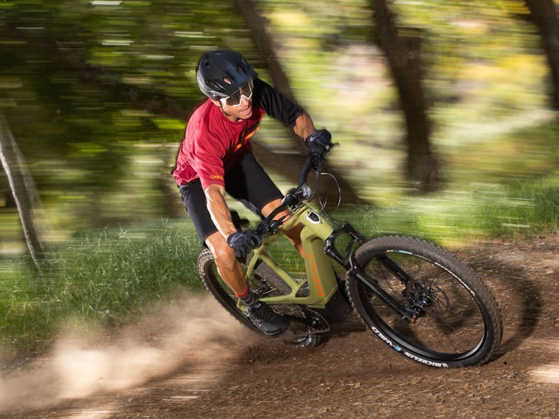 Mann fährt mit E-Mountainbike rasant durch einen Wald