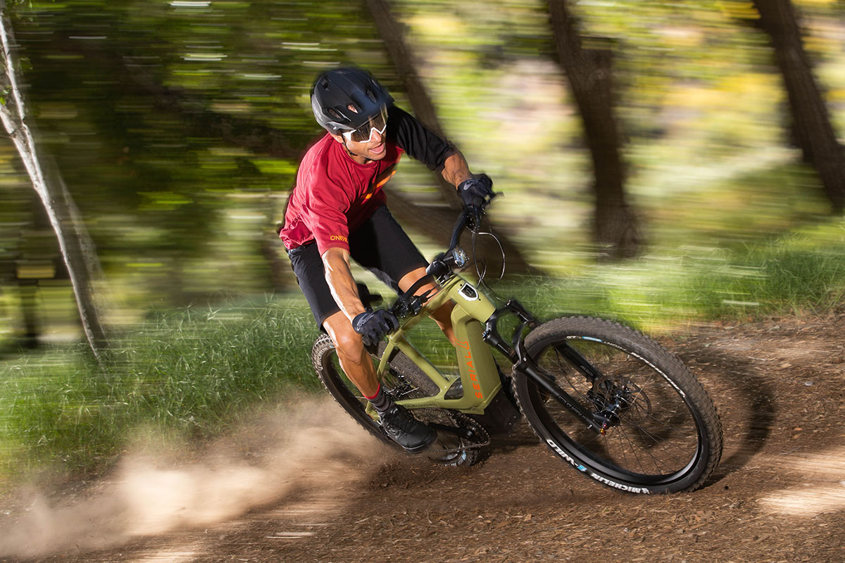 Mann fährt mit E-Mountainbike rasant durch einen Wald