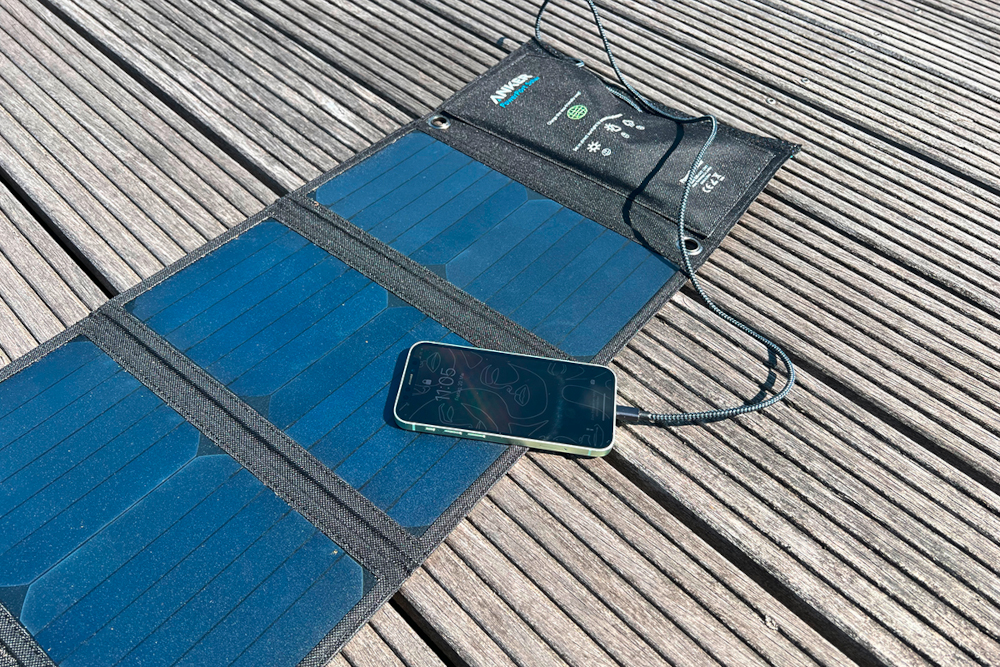 Eine Mini-Solartasche auf dem Boden lädt ein Smartphone auf.