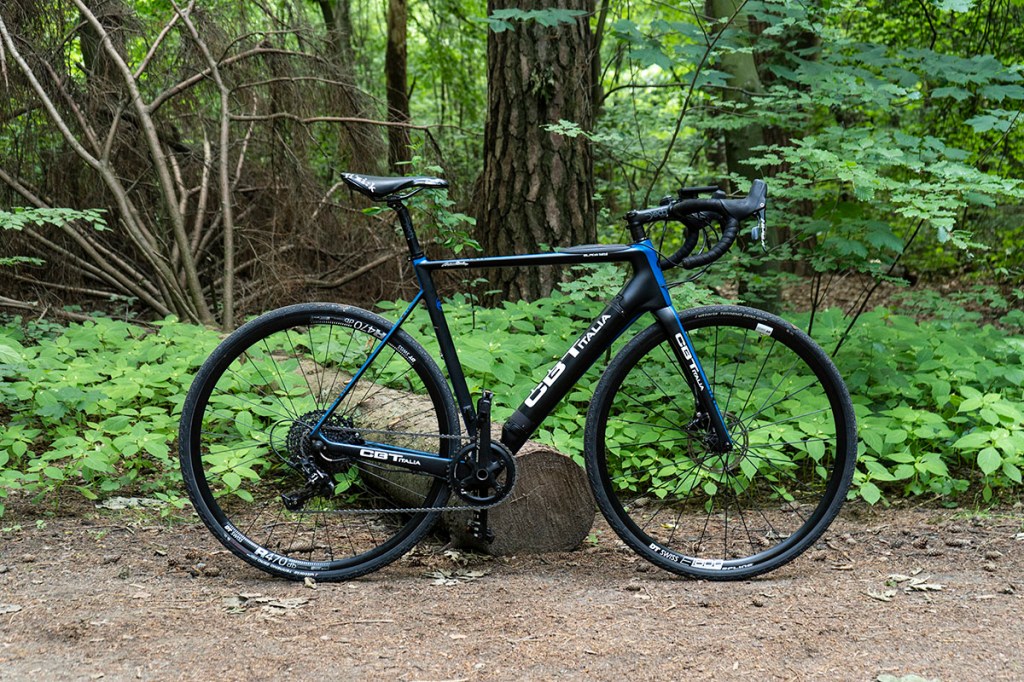 E-Gravel-Bike von C.B.T. Italia lehnt an einem Baumstamm im Wald