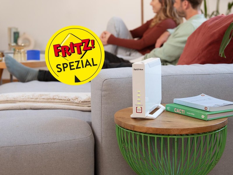 Eine Fritzbox im Wohnzimmer mit TV-guckendem Paar im Hintergrund