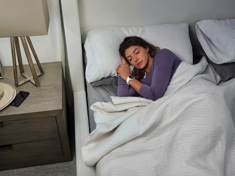 Frau im Bett mit Smartwatch