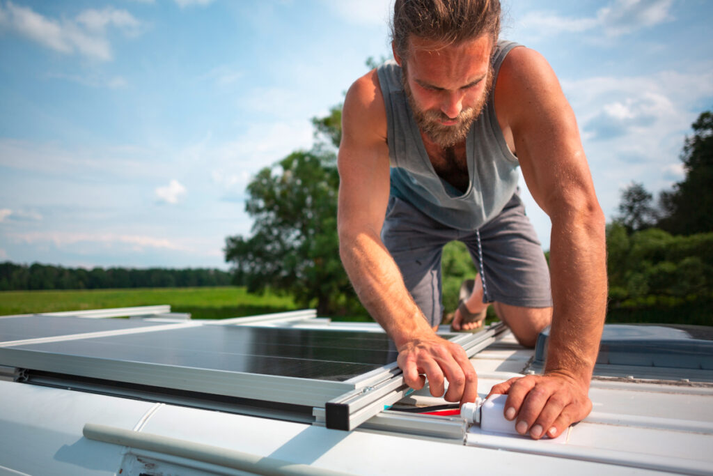 Ein Mann befestigt das Solarpanel am Dach des Wohnmobils.