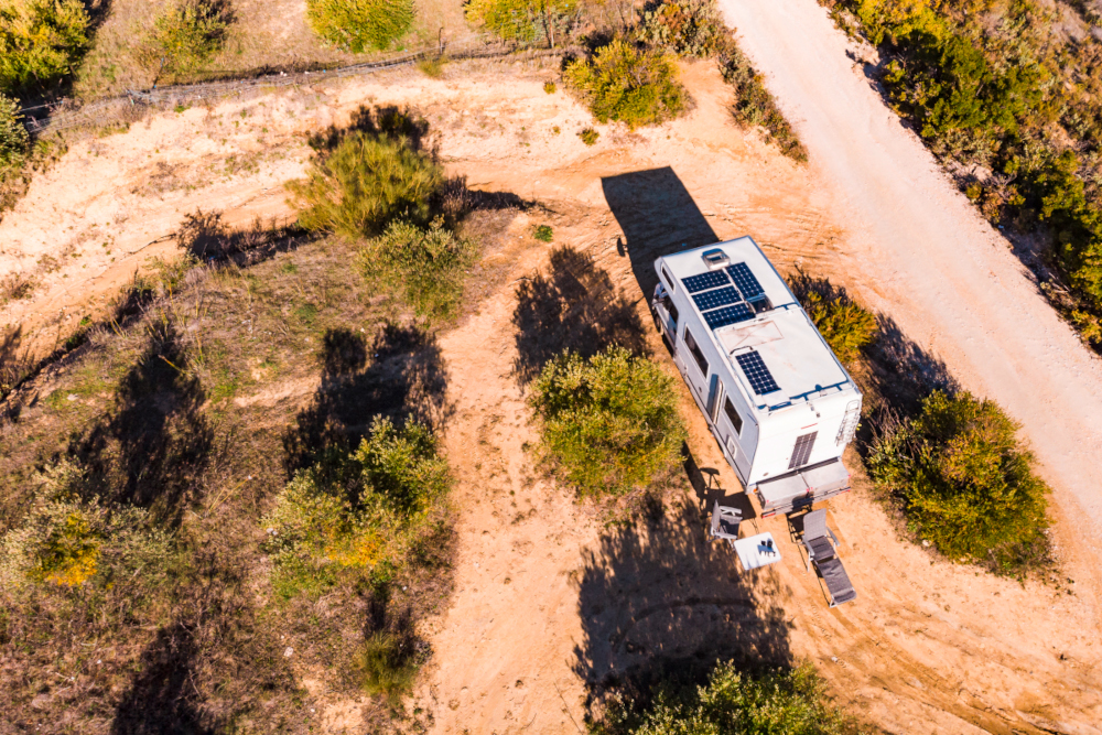 Eine Luftaufnahme eines Wohnmobil welches seine Batterien mit einem Solarpanel auflädt.