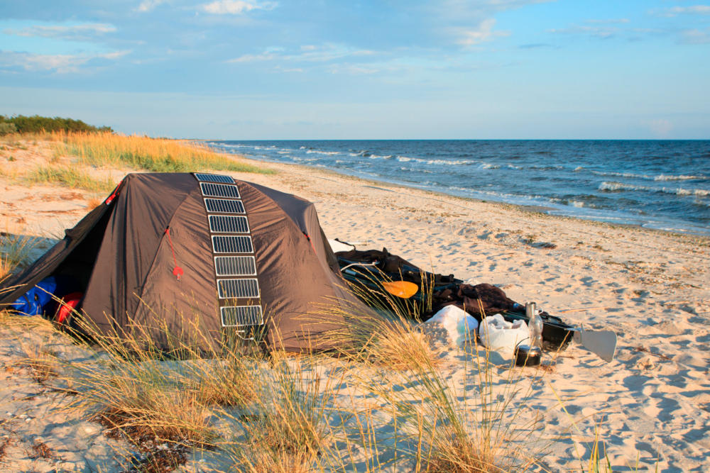Ein Zelt am Strand mit einem übergelegten Solarpanel.