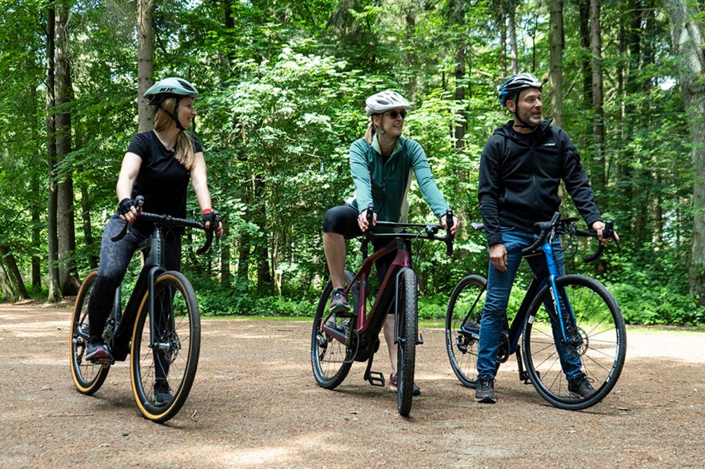 Zwei Frauen und ein Mann mit E-Gravel-Bikes im Wald