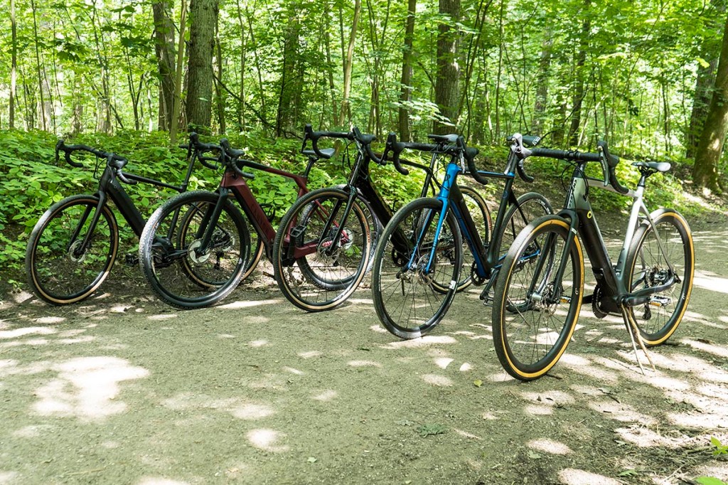 Fünf E-Gravel-Bikes aufgereiht nebeneinander auf einem Waldweg