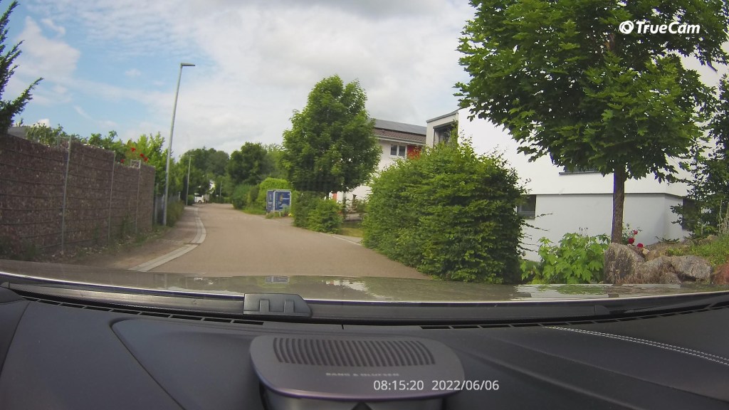 Aufnahmebild von Dashcam zeigt Weg mit Büschen und Häusern