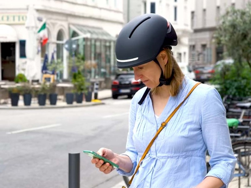 Nahaufnahme Frau mit einem schwarzen Fahrradhelm, schaut auf ihr Smartphone