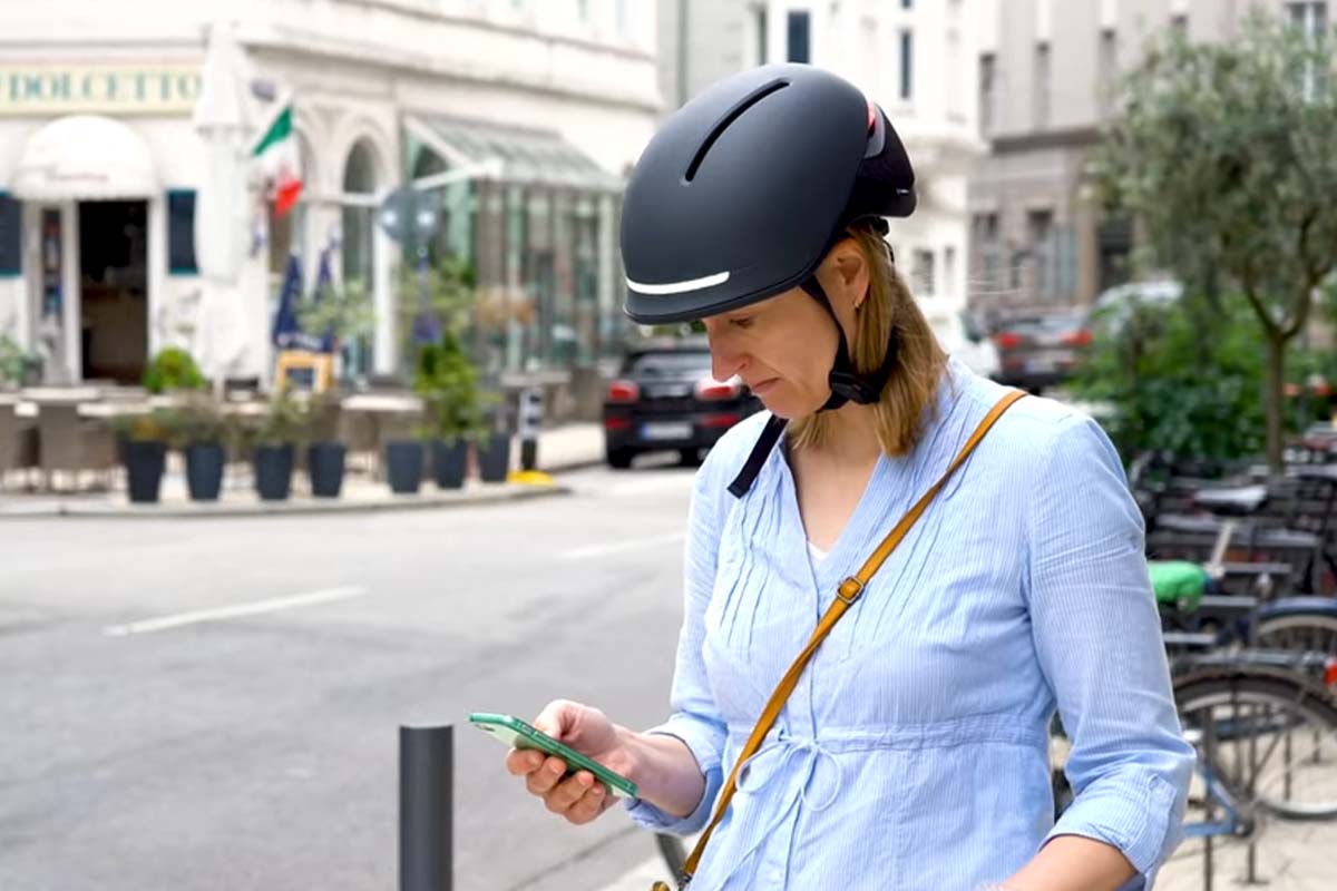 Nahaufnahme Frau mit einem schwarzen Fahrradhelm, schaut auf ihr Smartphone