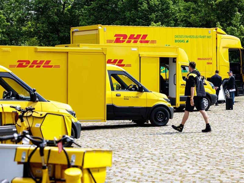 Verschiedene Fahrzeuge der DHL Group sind zu sehen.