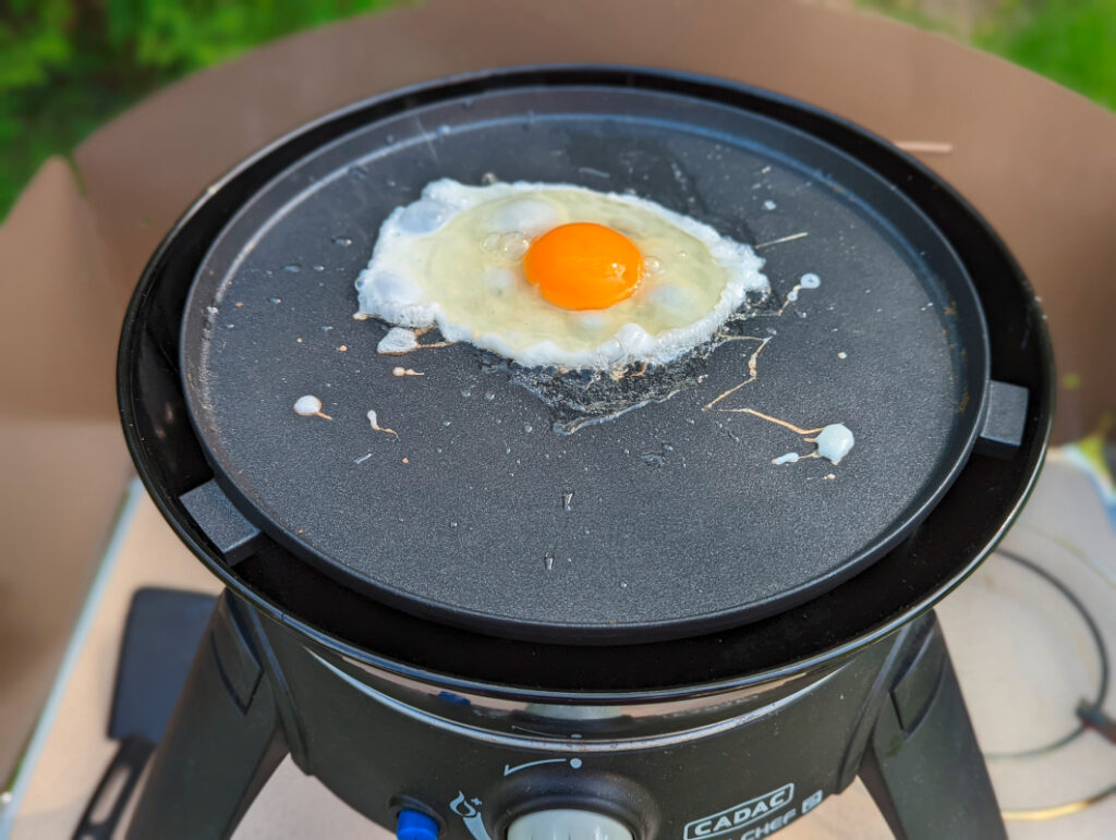 Schwarze Platte auf mobilen Gasgrill mit Spiegelei