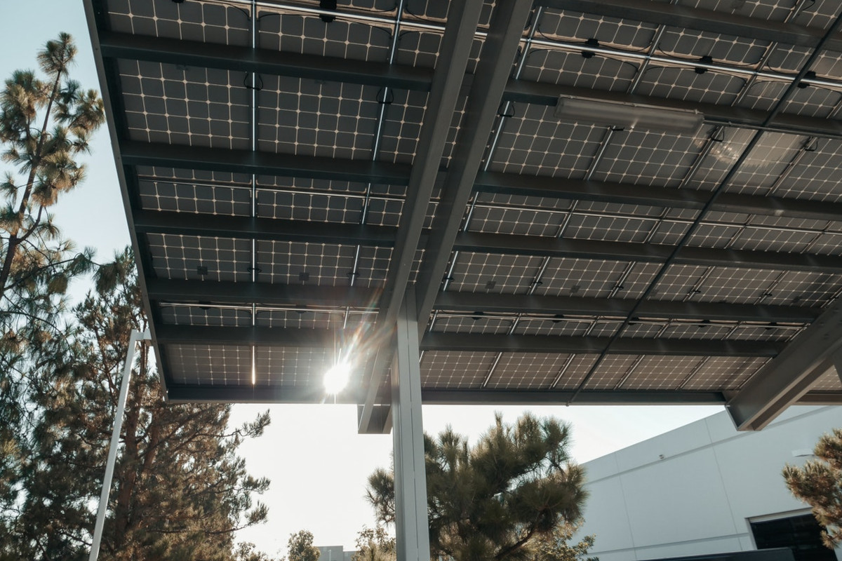 Solarcarport von unten mit Bäumen im Hintergrund und weißem Gebäude