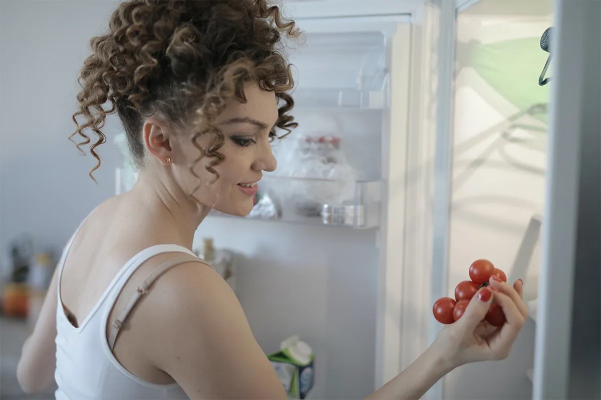 Eine Frau ein Bund Tomaten aus einem Kühlschrank.