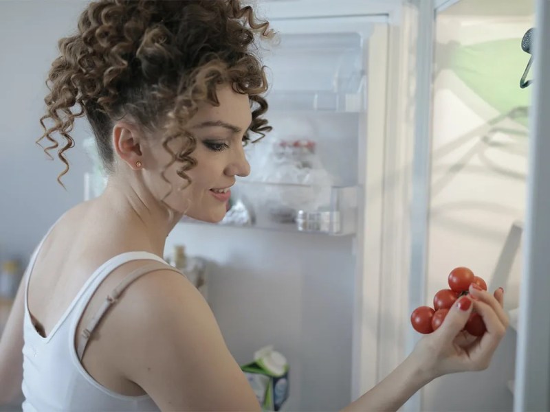 Eine Frau ein Bund Tomaten aus einem Kühlschrank.