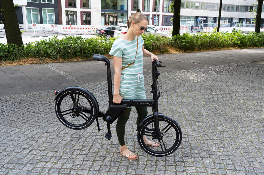 E-Faltrad von Honbike, Frau trägt Fahrrad
