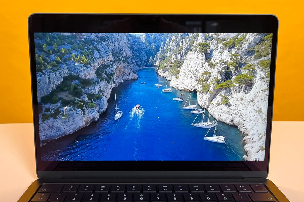 Apple MacBook Air Display zeigt blau schimmerndes Meer zwischen zwei Berghängen