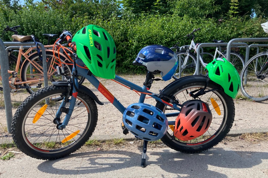 Totale: Fahrrad mit fünf Kinder-Fahrradhelmen, die am Rahmen und Lenker befestigt sind