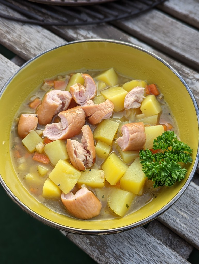 Eine Schale mit Kartoffelsuppe und Bockwurst