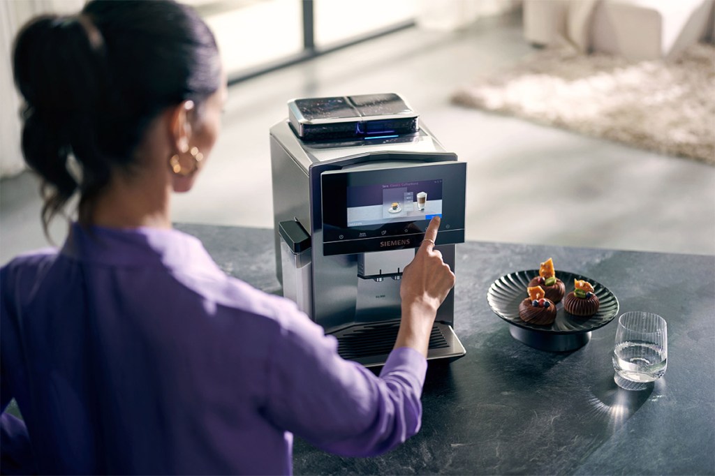 Es ist eine Person zu sehen, die das Display des neuen Siemens EQ900-Kaffeevollautomaten bedient.