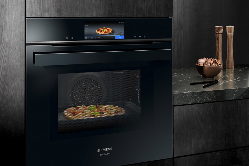 Auf dem Bild ist der neue Siemens iQ700-Backofen gezeigt. Im Backofen befindet sich eine Pizza und auf dem Bedien-Display ist ebenfalls eine Pizza als Foto zu sehen.